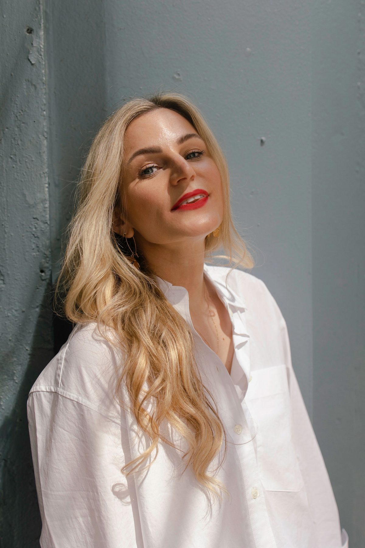 Kiera Doyle, Vitality Project coach, smiling in sunlight against a grey wall