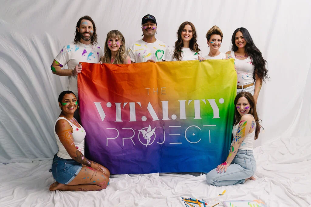 A salon team holding The Vitality Project flag