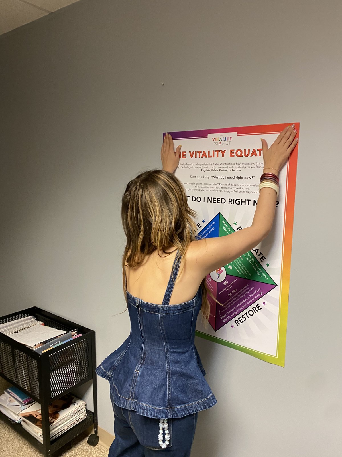 A student pinning up The Vitality Equation poster