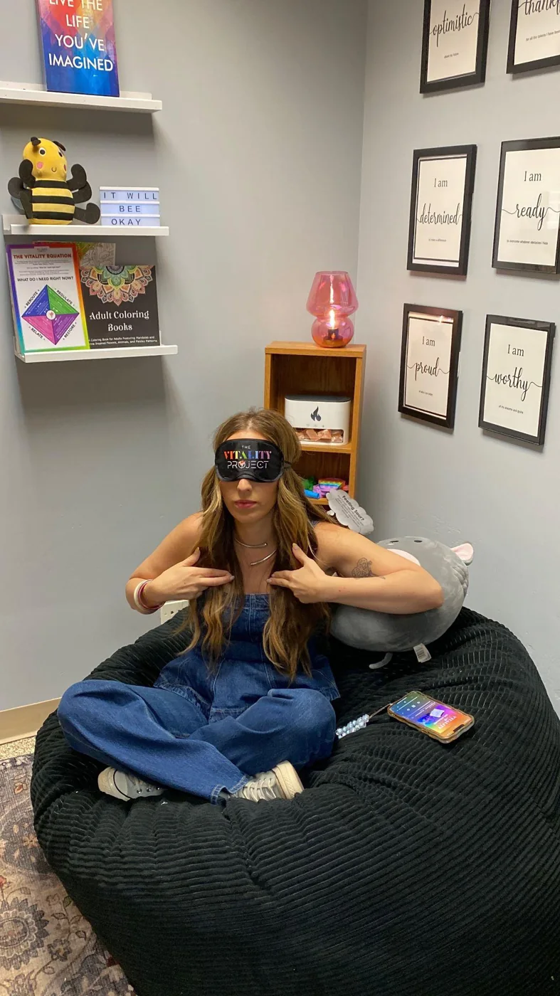A student resting on the bean bag in a Vitality Pod wearing the Vitality Project eye mask