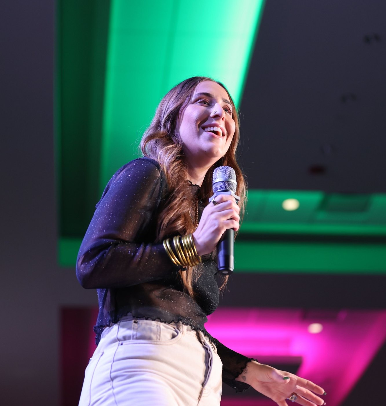 Elizabeth Faye delivering a keynote under green stage light