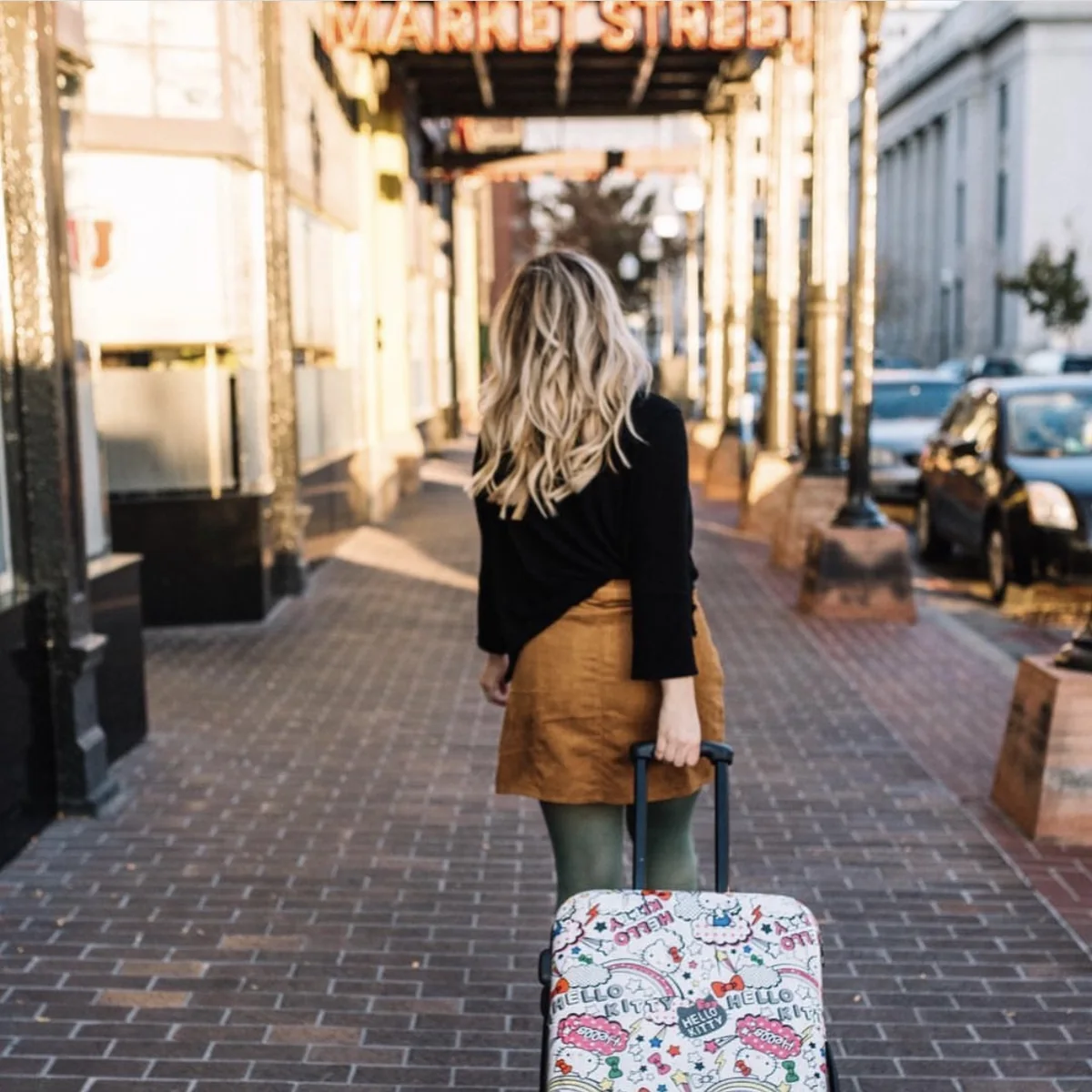 Elizabeth Faye walking down Market Street pulling a suitcase