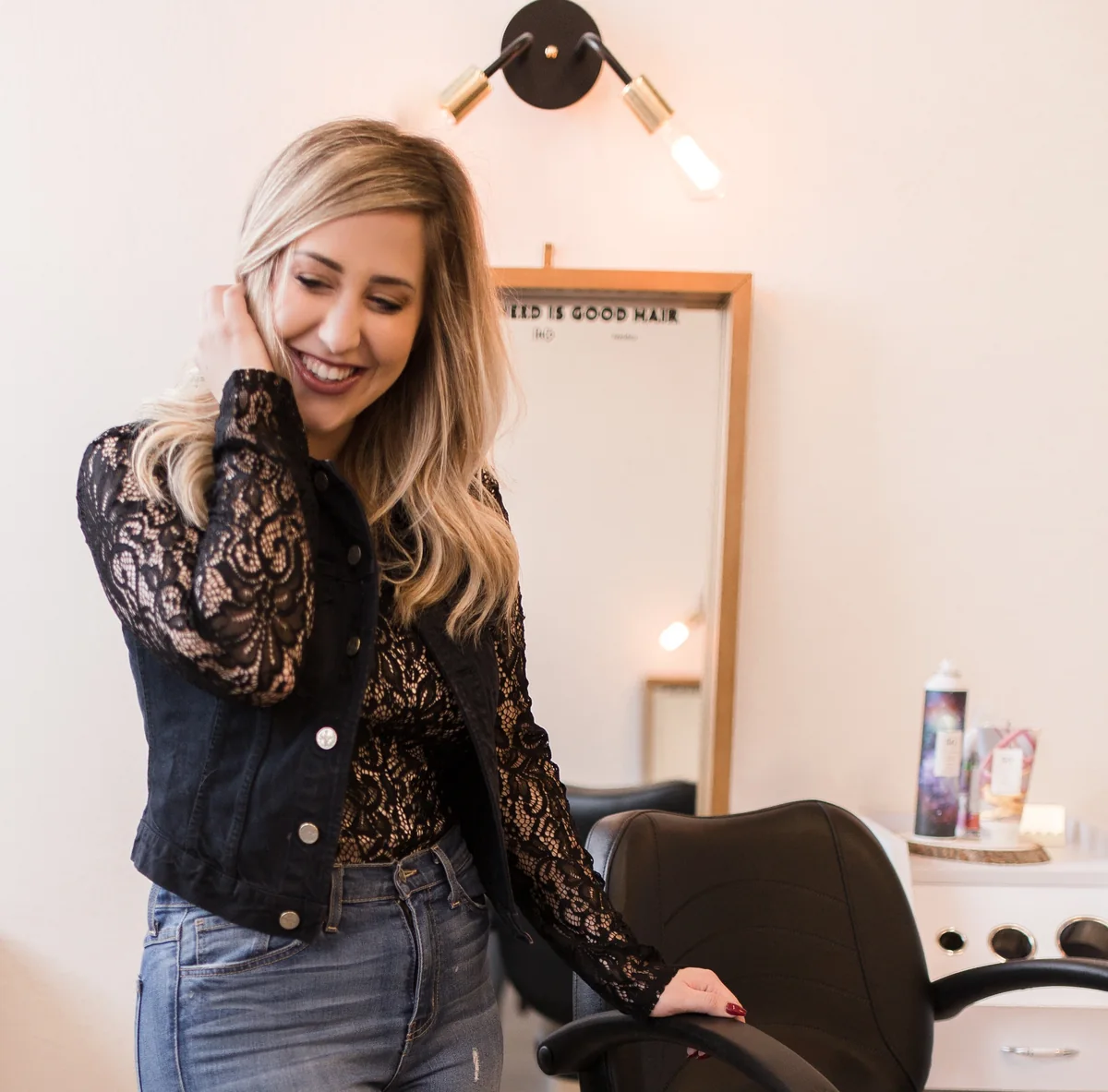 Elizabeth Faye laughing beside the chair at Elizabeth Faye Salon
