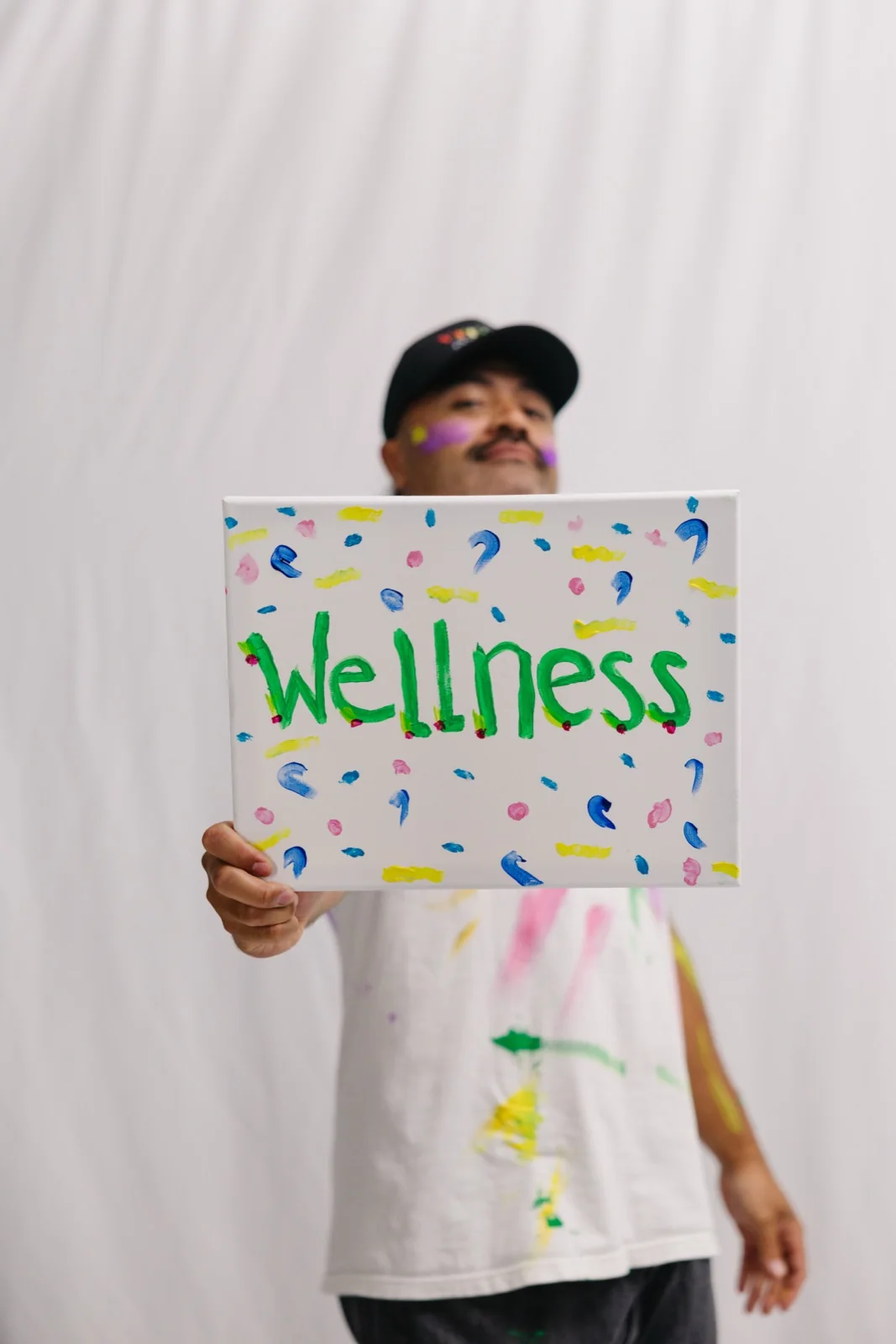 Team member holding a hand-painted Wellness sign